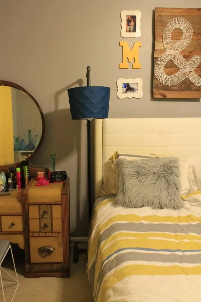 A wider photo of the pipe lamp next to a bed.