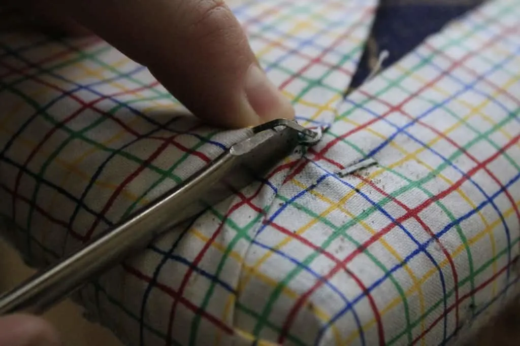 A photo of someone using pliers to remove staples from a bench. 