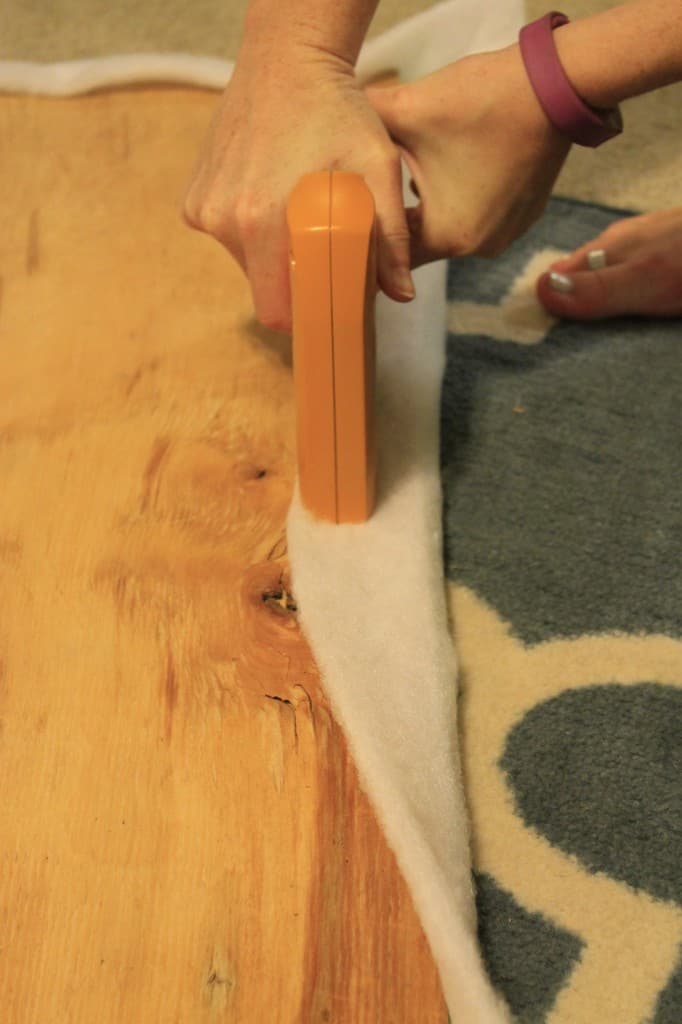 A photo of the foam being stapled to the wooden seat board. 