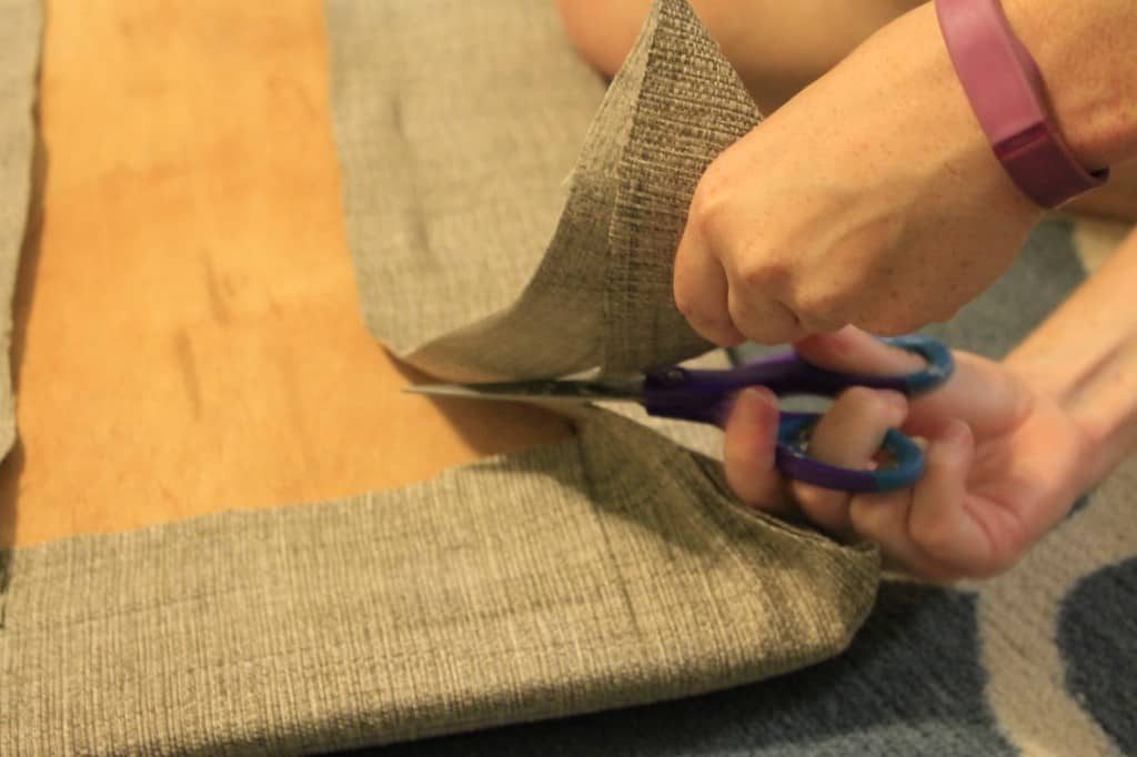 A photo of the upholstery fabric being trimmed with scissors at the corners. 