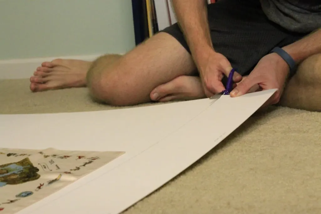 A photo of a man cutting matting board with scissors