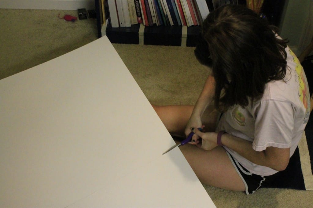 A photo of a woman cutting matting board with scissors