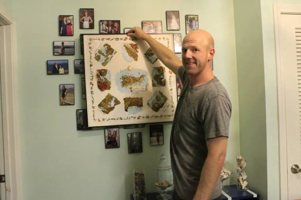 A photo of a man hanging the framed scarf on a wall