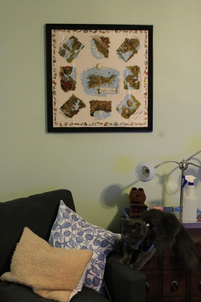 A photo of the framed scarf above the living room chair