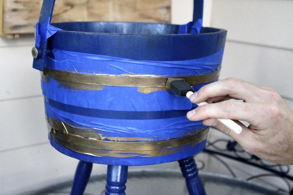 A photo of gold paint being brushed onto the planter. 