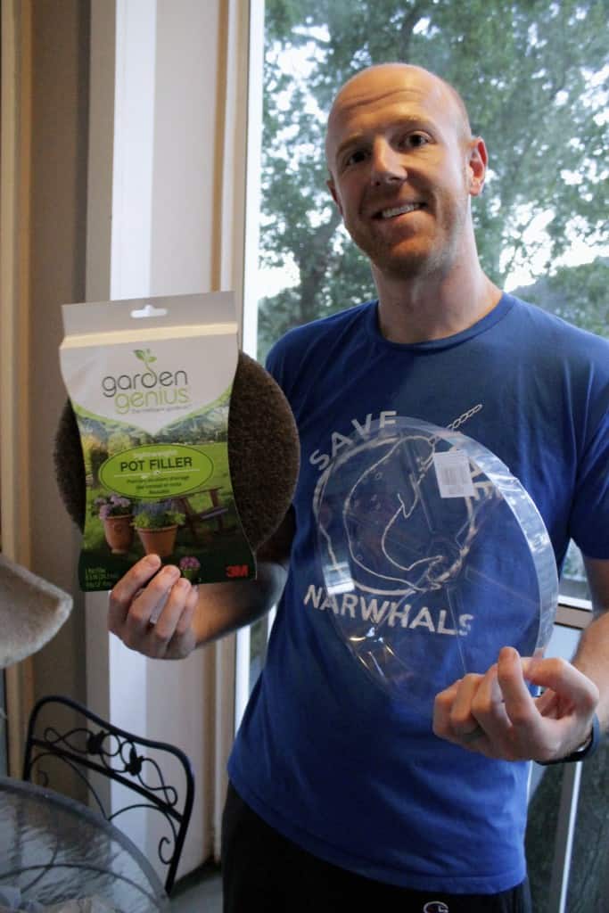 A photo of a man holding up a packet of plant filler. 