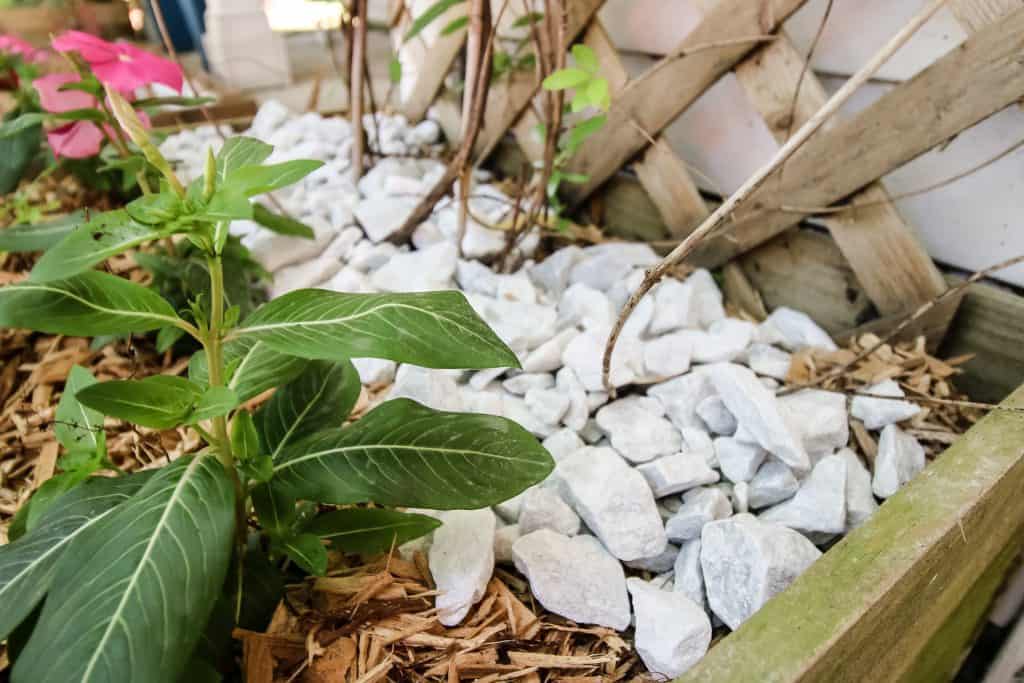 adding pebbles to a flower bed to prevent erosion