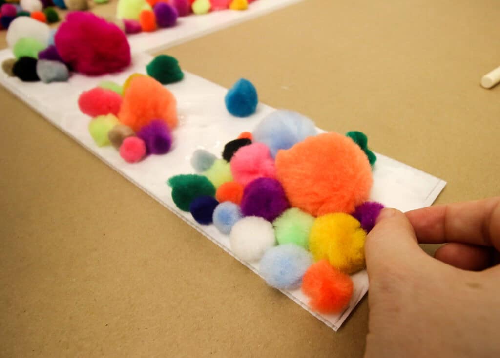 applying pom poms to create large pom pom letters