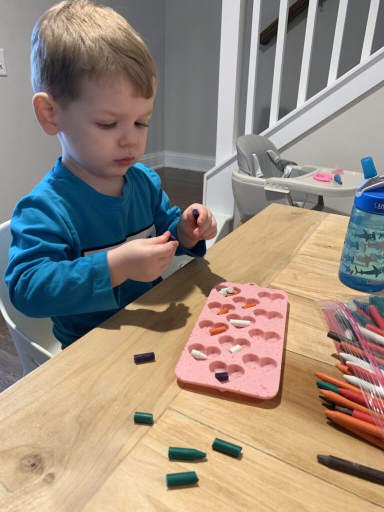 toddler breaking up crayons to melt into shapes