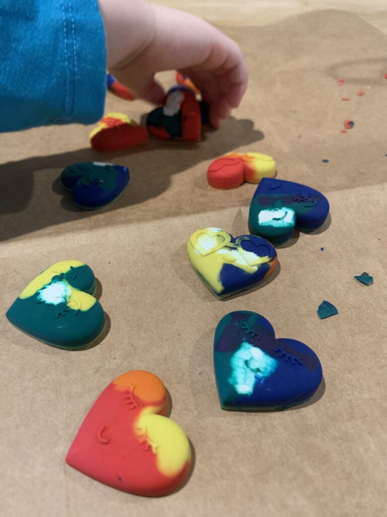 toddler hands coloring with heart shaped crayons