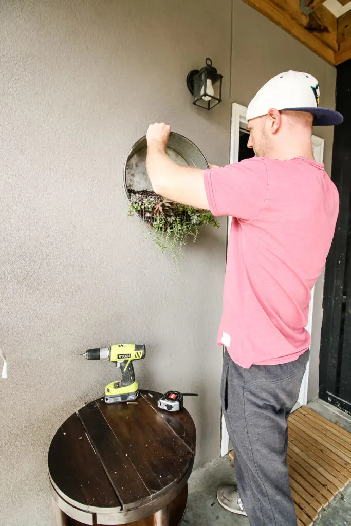hanging a galvanized metal wall planter on a patio wall using 2 screws and d hooks