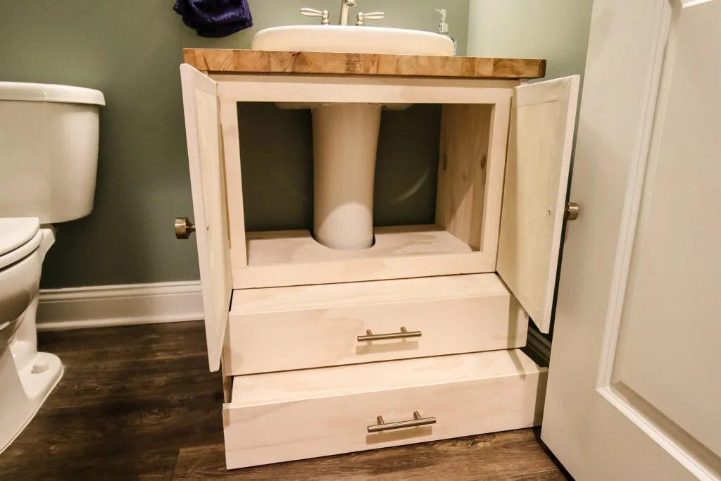 Pedestal sink vanity with cabinet doors open and steps pulled out
