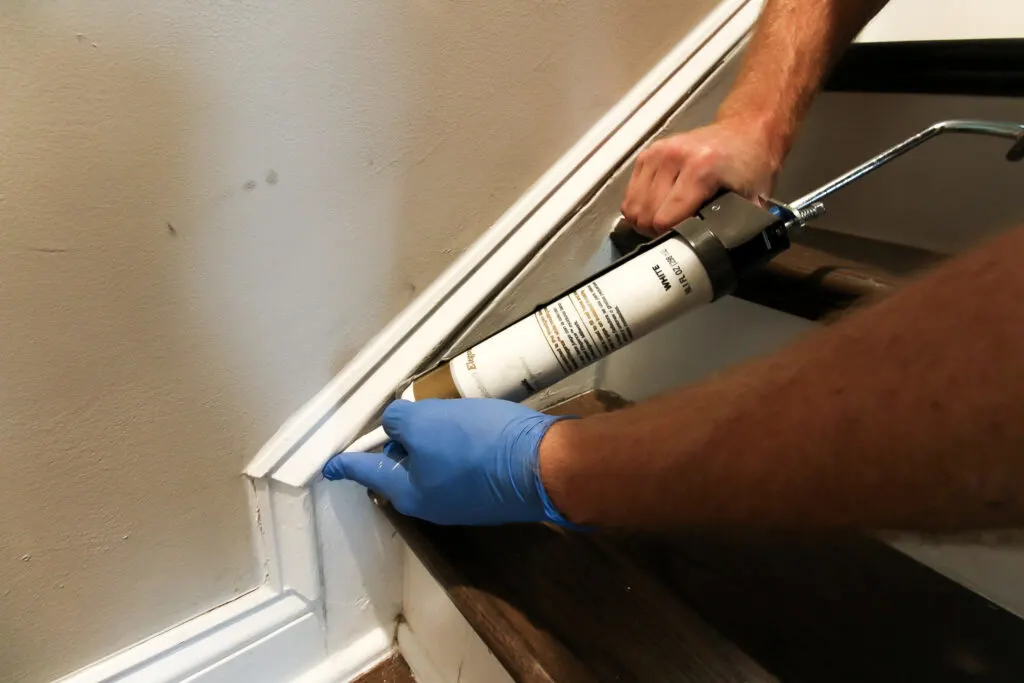 Applying new caulk to stairs