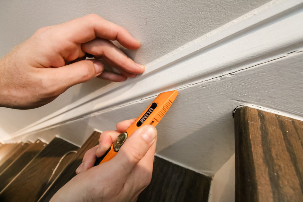 Cutting away dry, cracked caulk on stairs