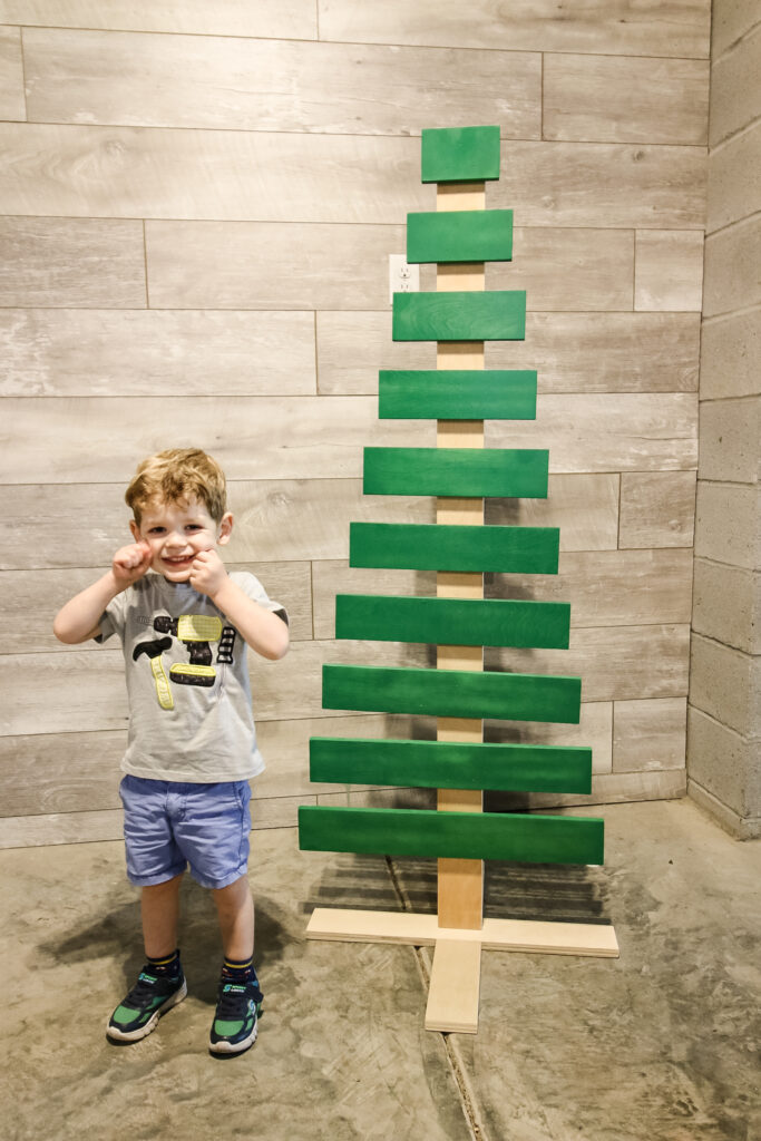 Toddler with wooden Christmas tree