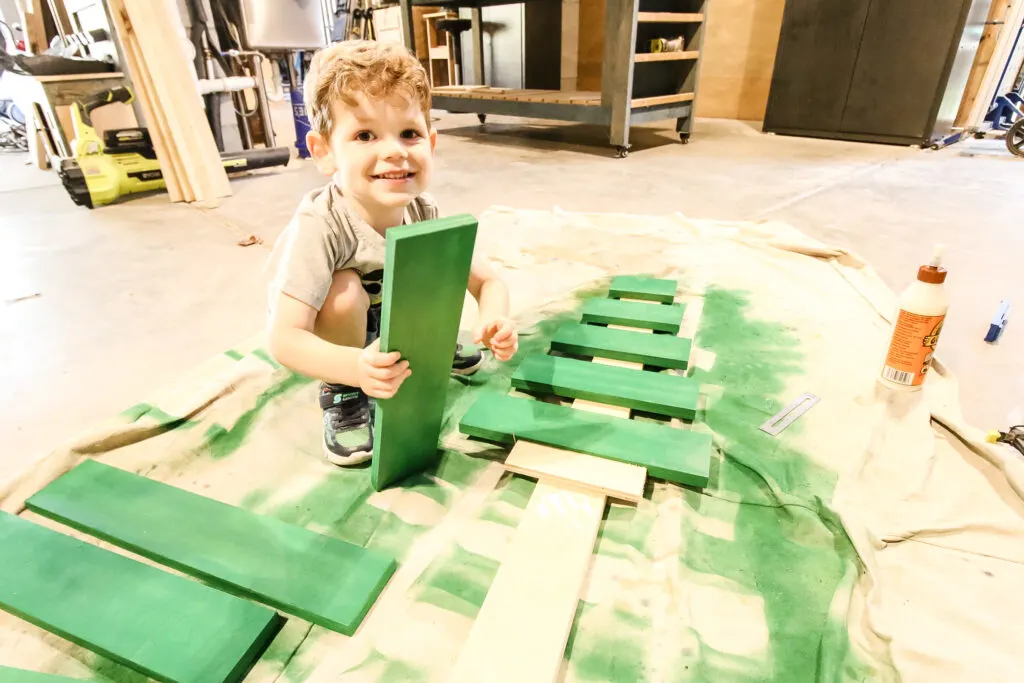 Toddler helping build wooden slat christmas tree