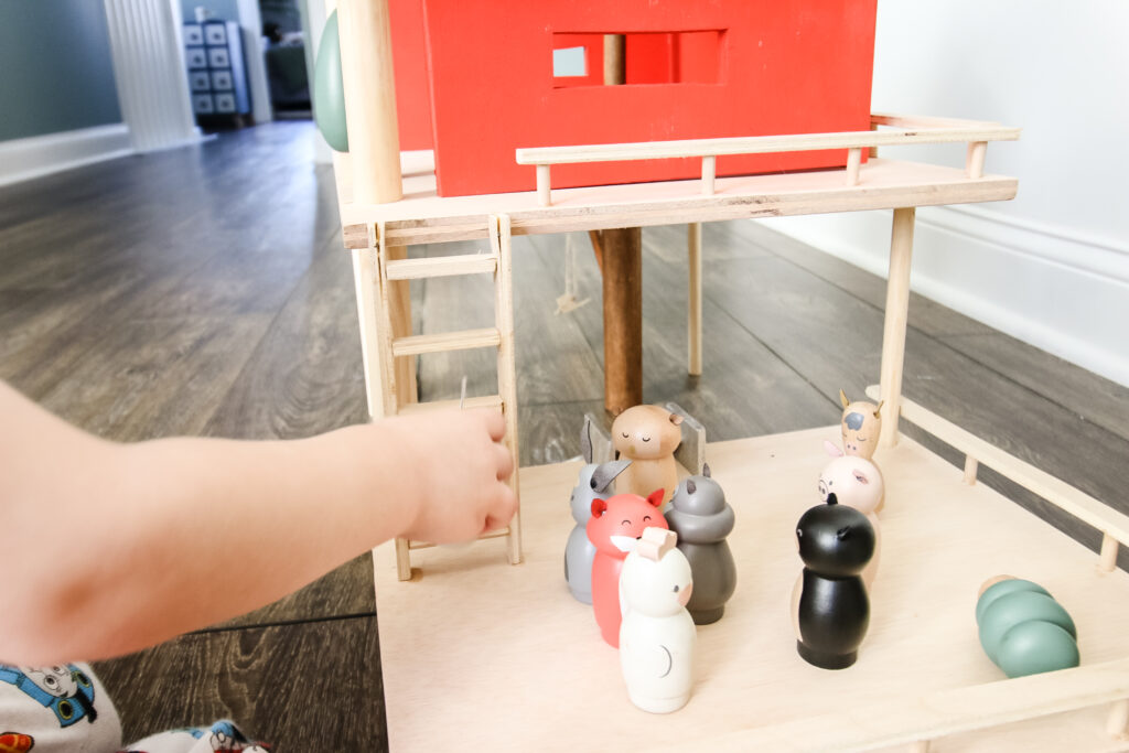 Moving peg dolls around wooden toy treehouse