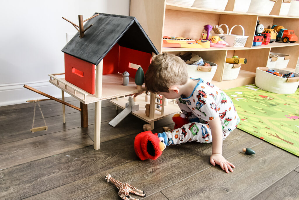 Toddler playing with wooden toy treehouse