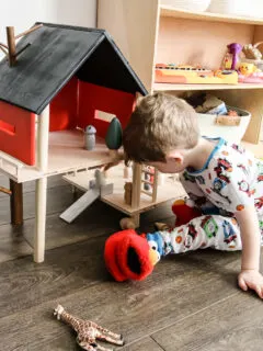 Toddler playing with wooden toy treehouse