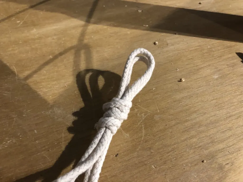 Rope tied around loops at top of hanging plant shelf