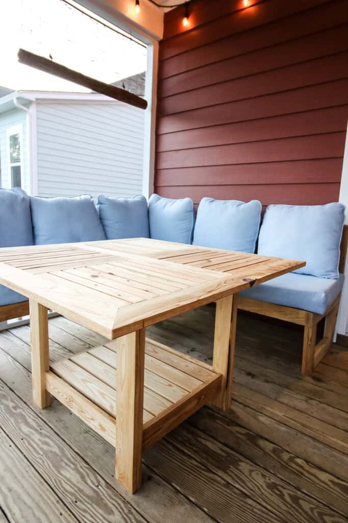 Tall view of DIY square outdoor dining table with string lights and couch