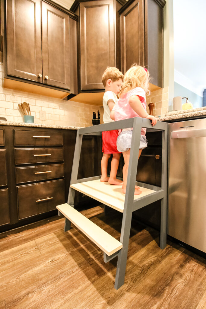 Toddlers baking standing on DIY double kids learning tower