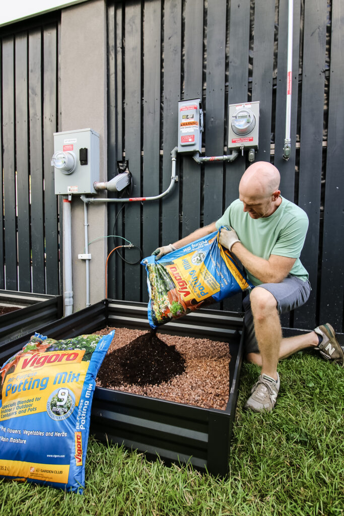 Pouring Vigoro potting soil in raised garden bed