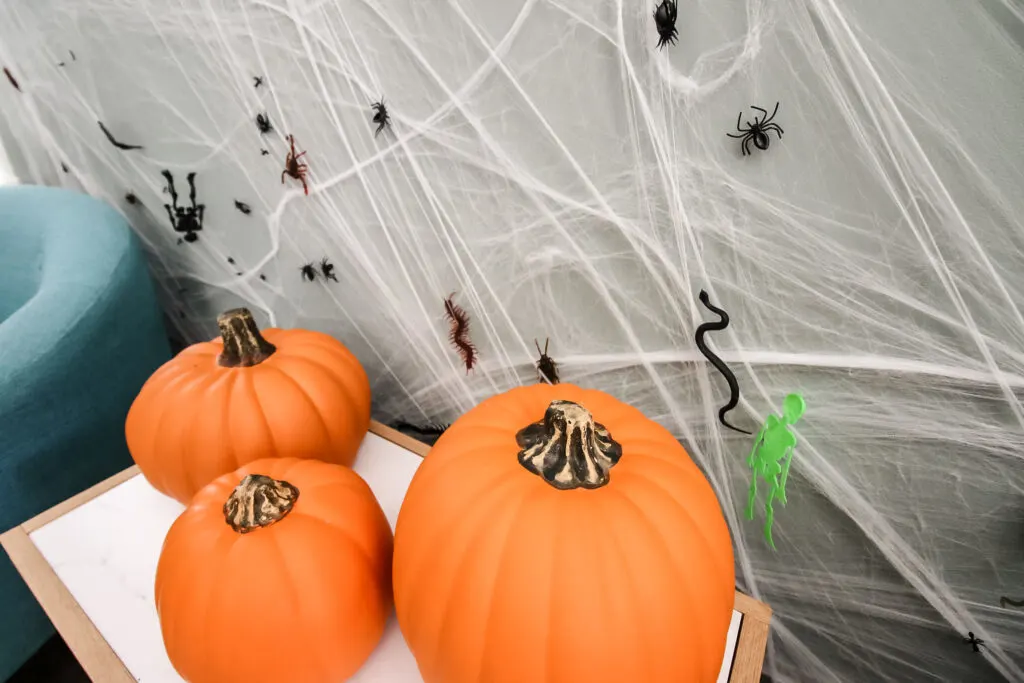 faux spiderweb behind halloween pumpkins