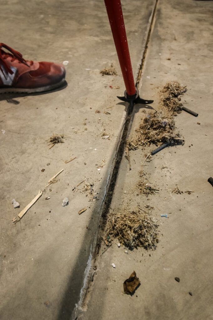 Sawdust and debris pulled from garage workshop cracks