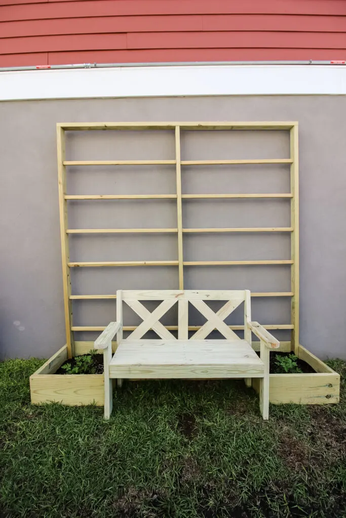 Straight on view of garden bench with raised garden and trellis