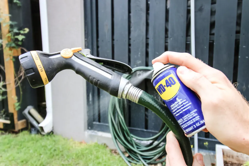 Spraying WD-40 onto stuck hose nozzle