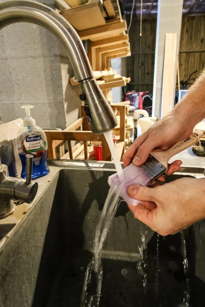 scrubbing a dirty paint brush in the sink