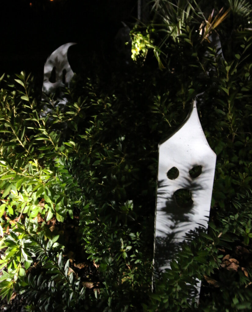 Wooden ghosts in bushes at night