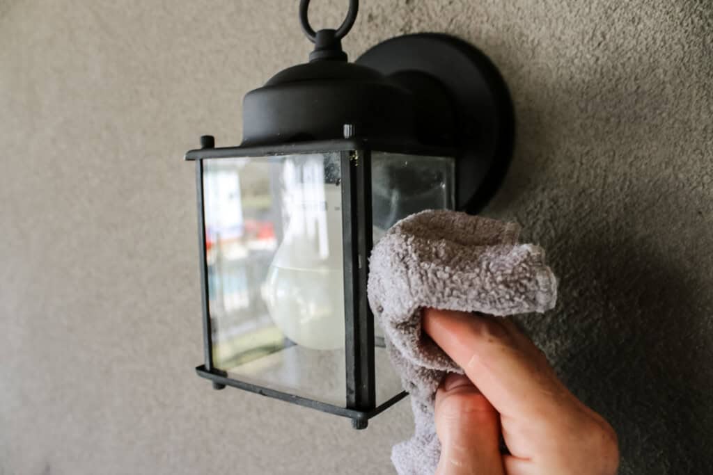 Wiping cleaned light fixture with wet rag