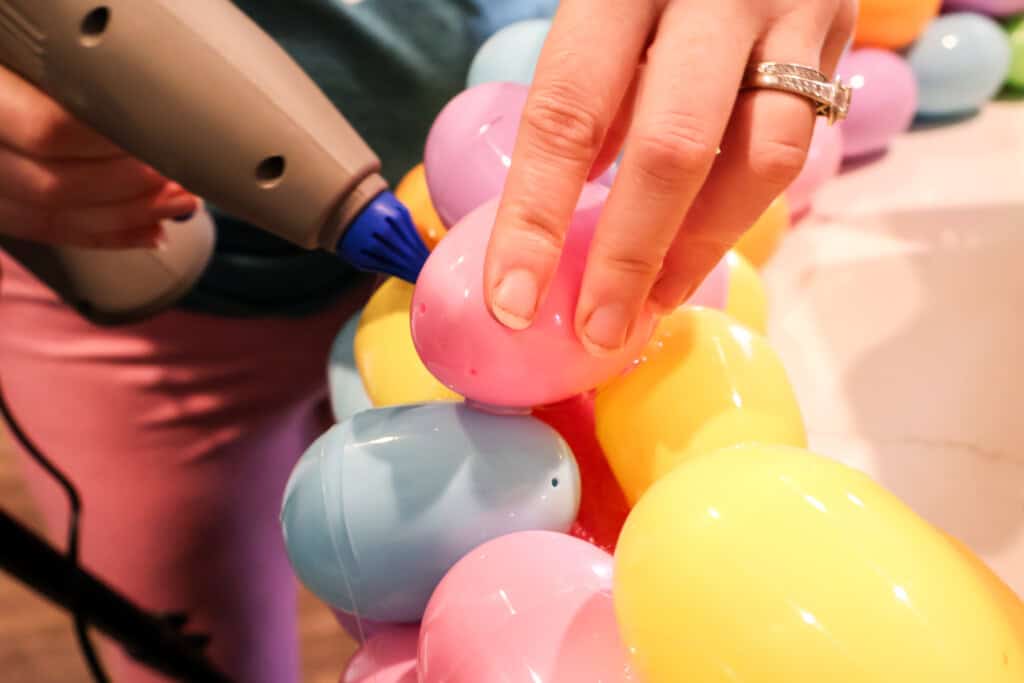 hot gluing easter eggs onto a wreath