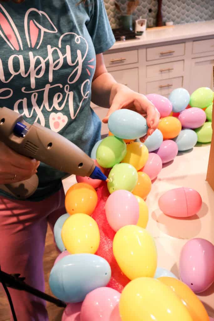hot gluing easter eggs onto a wreath