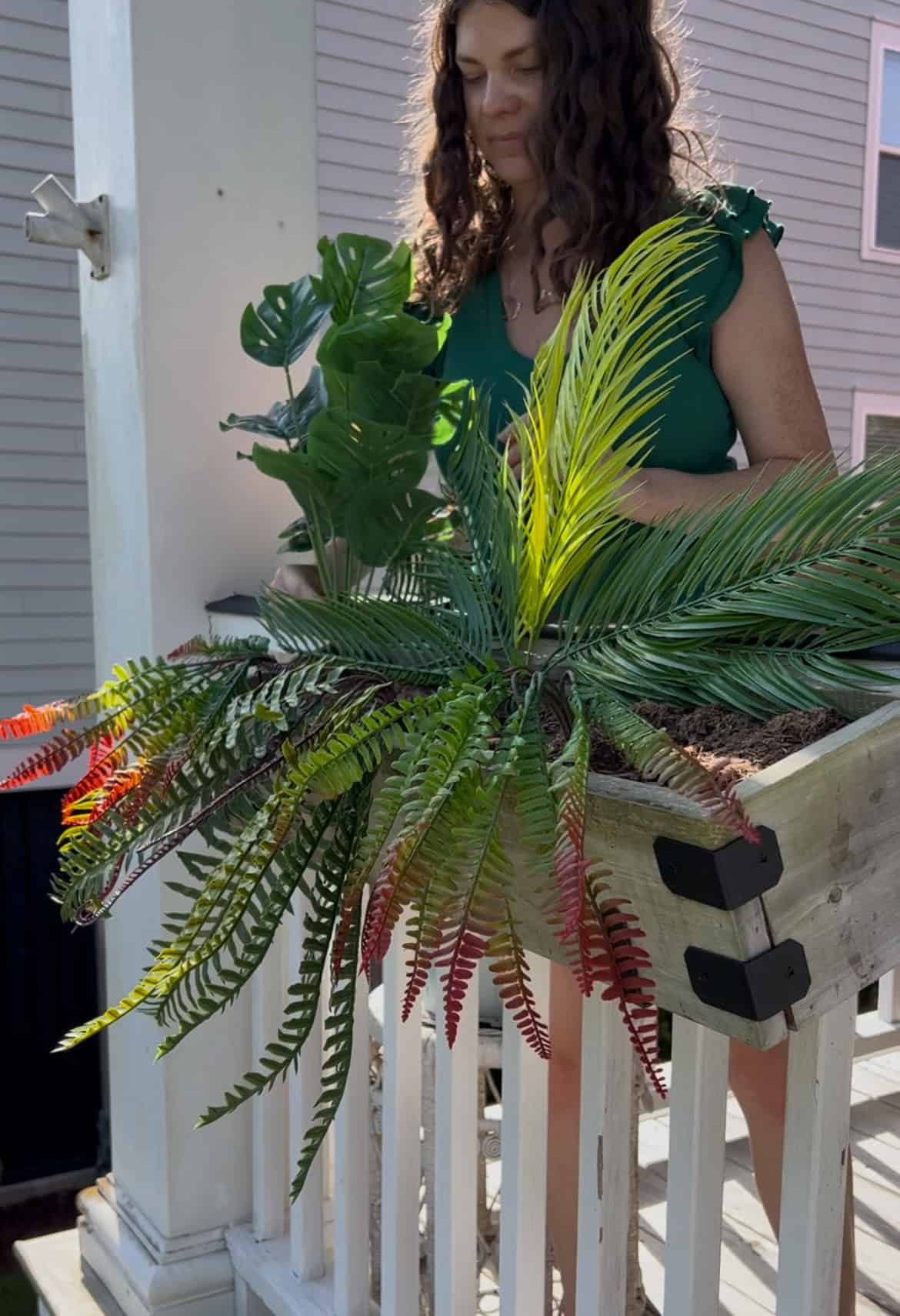 adding plants to a faux plant tropical windowbox planter