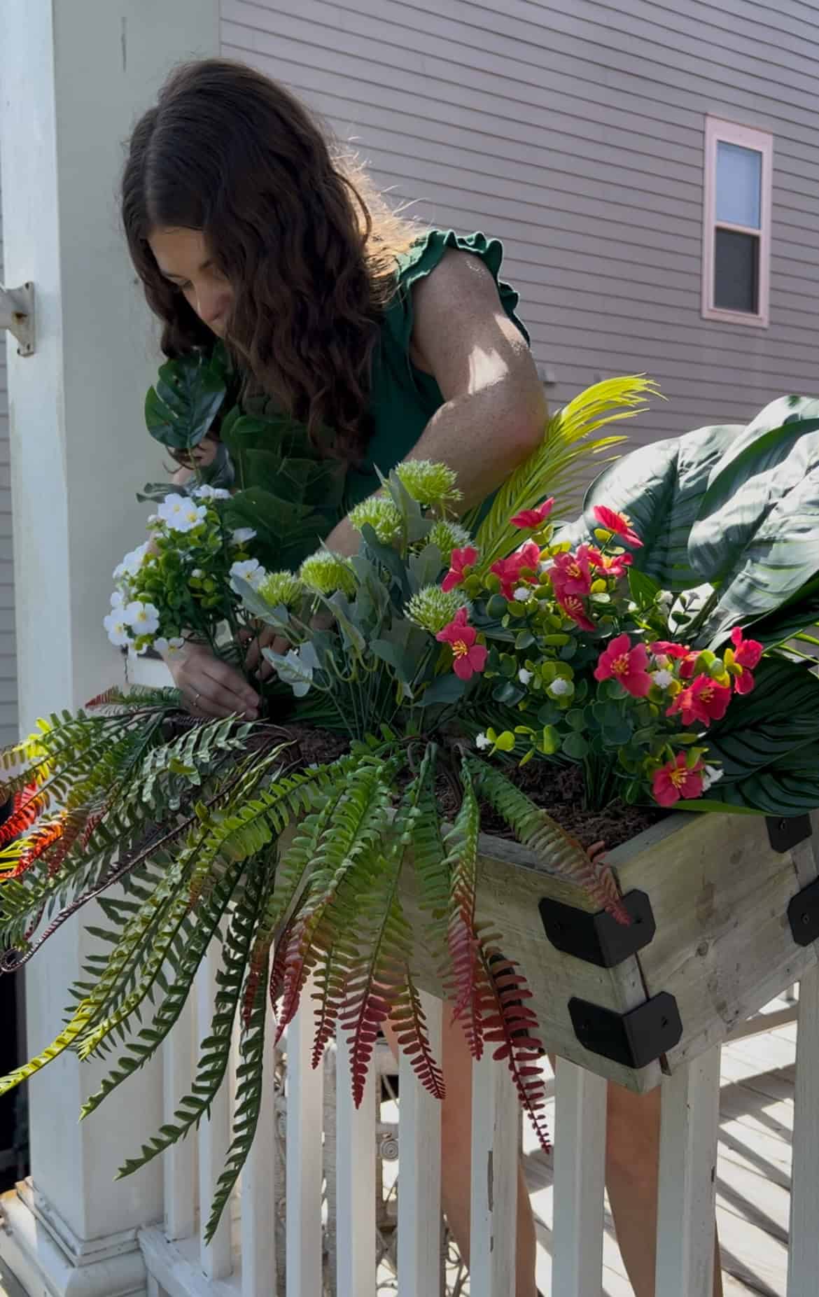 adding plants to a faux plant tropical windowbox planter